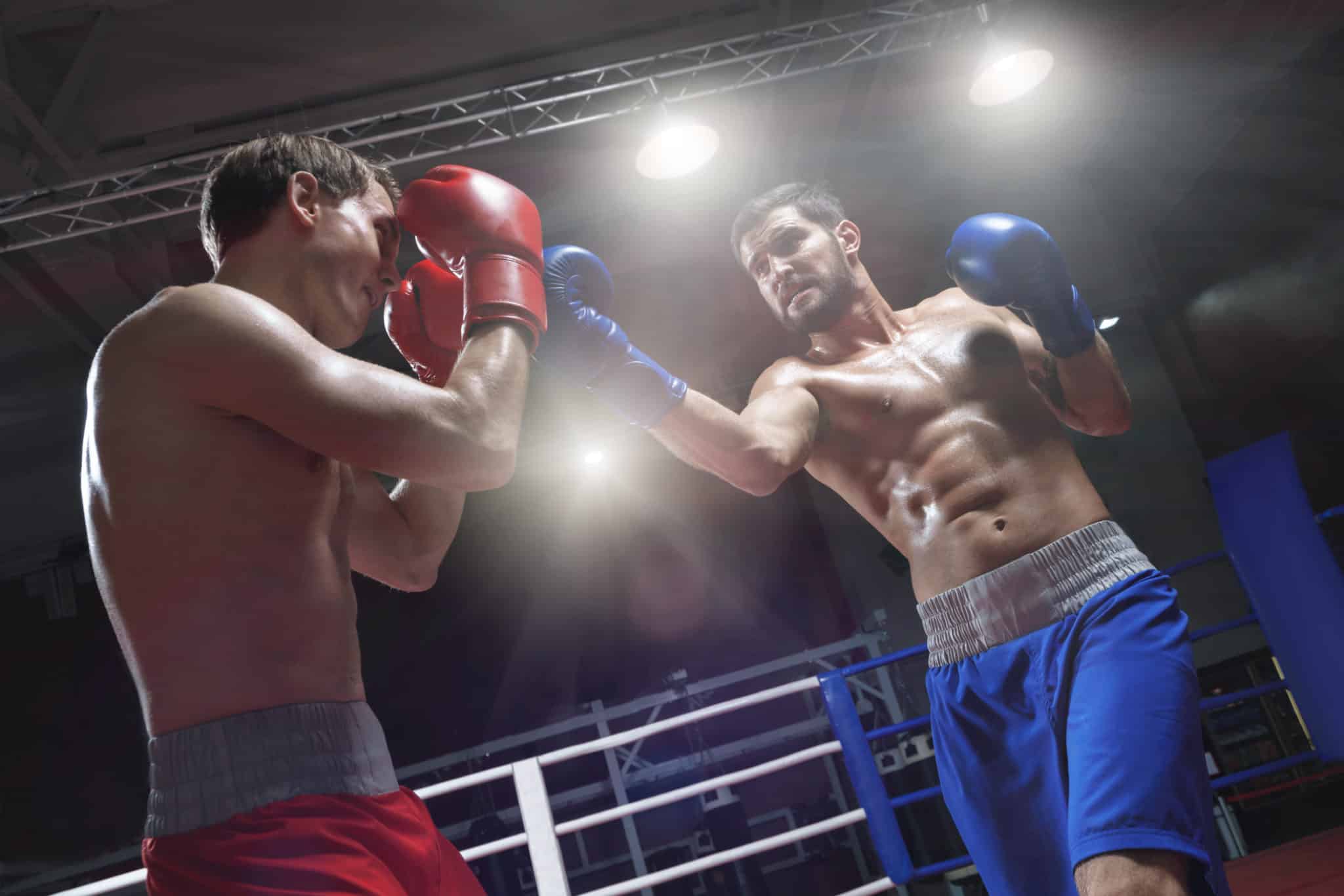 Zwei Boxer im Scheinwerferlicht beim kämpfen im Ring.