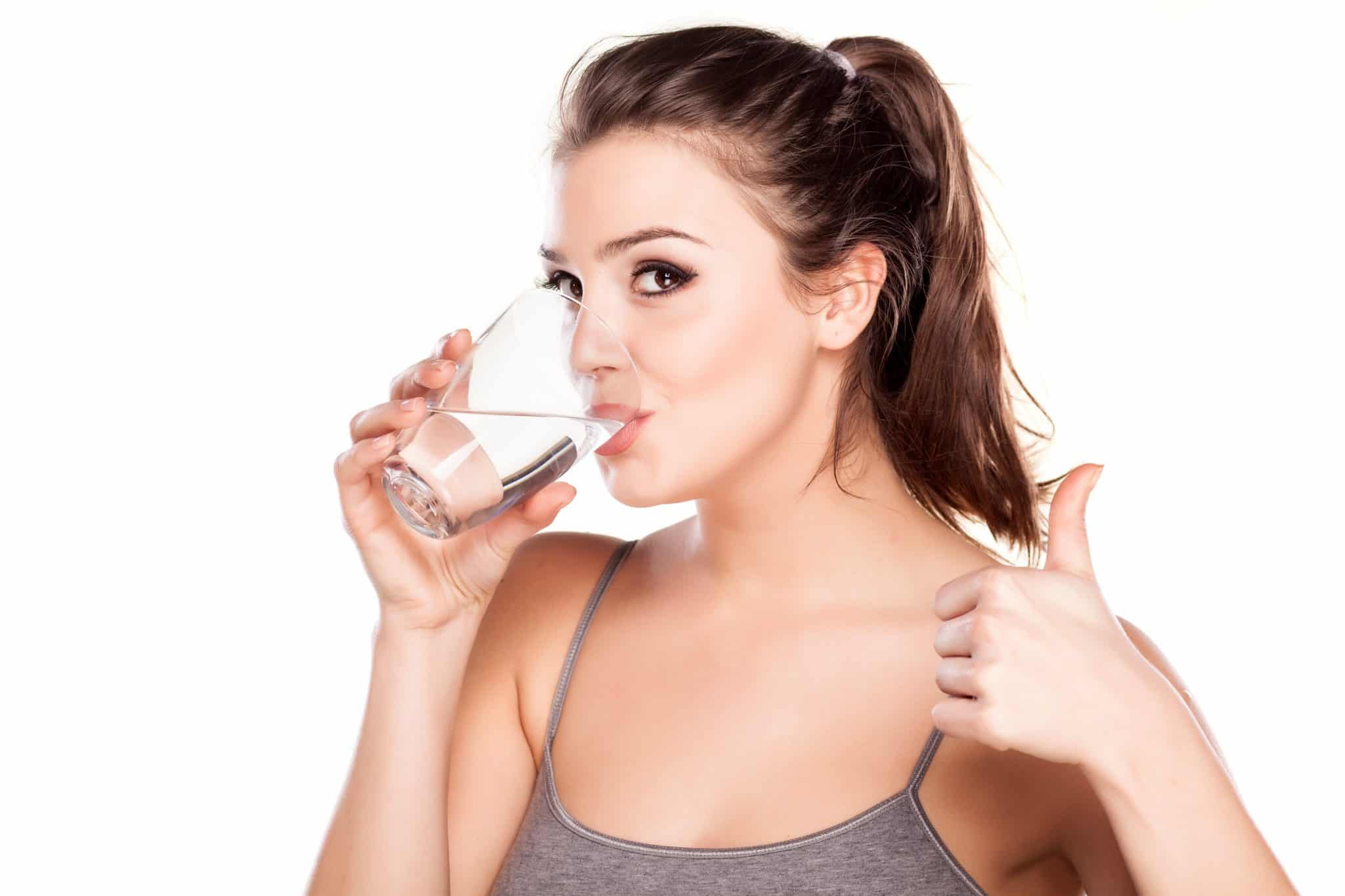 Frau trinkt Wasser mit Daumen nach oben