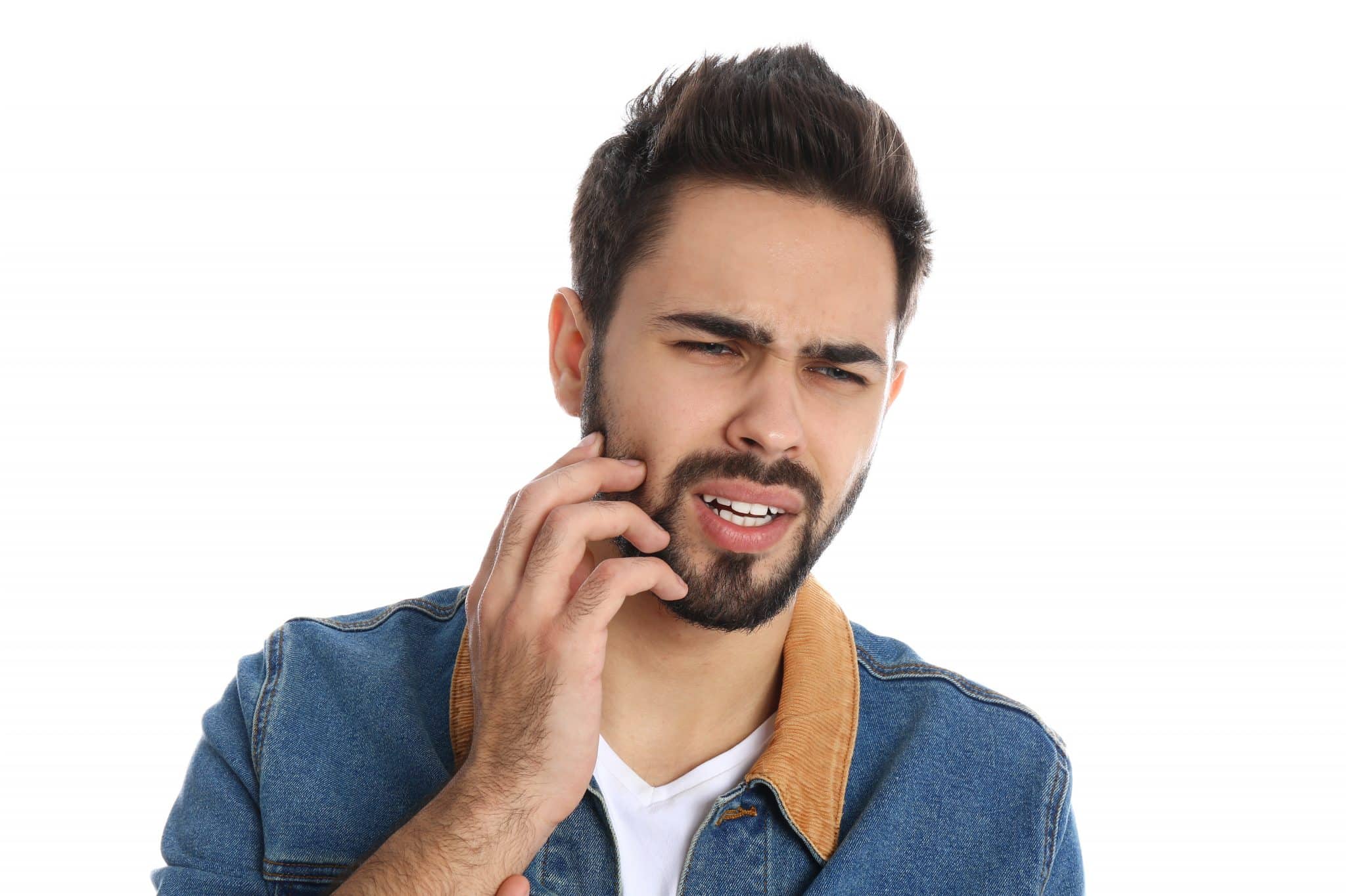 Ein junger Mann mit starken Zahnschmerzen hält sich die Hand an die schmerzende Wange.