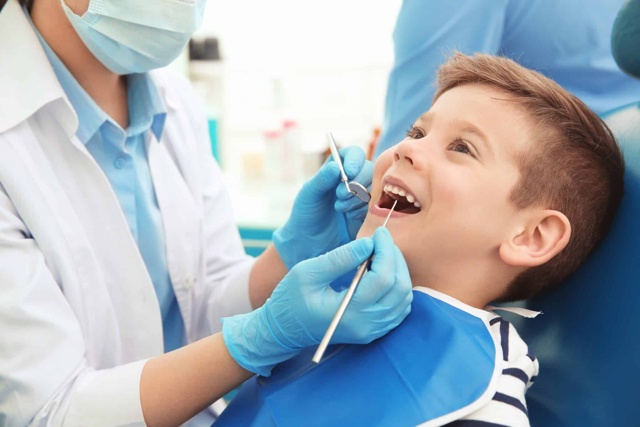 Ein Zahnarzt untersucht die Milchzähne eines kleinen Jungen in der Zahnarztpraxis.