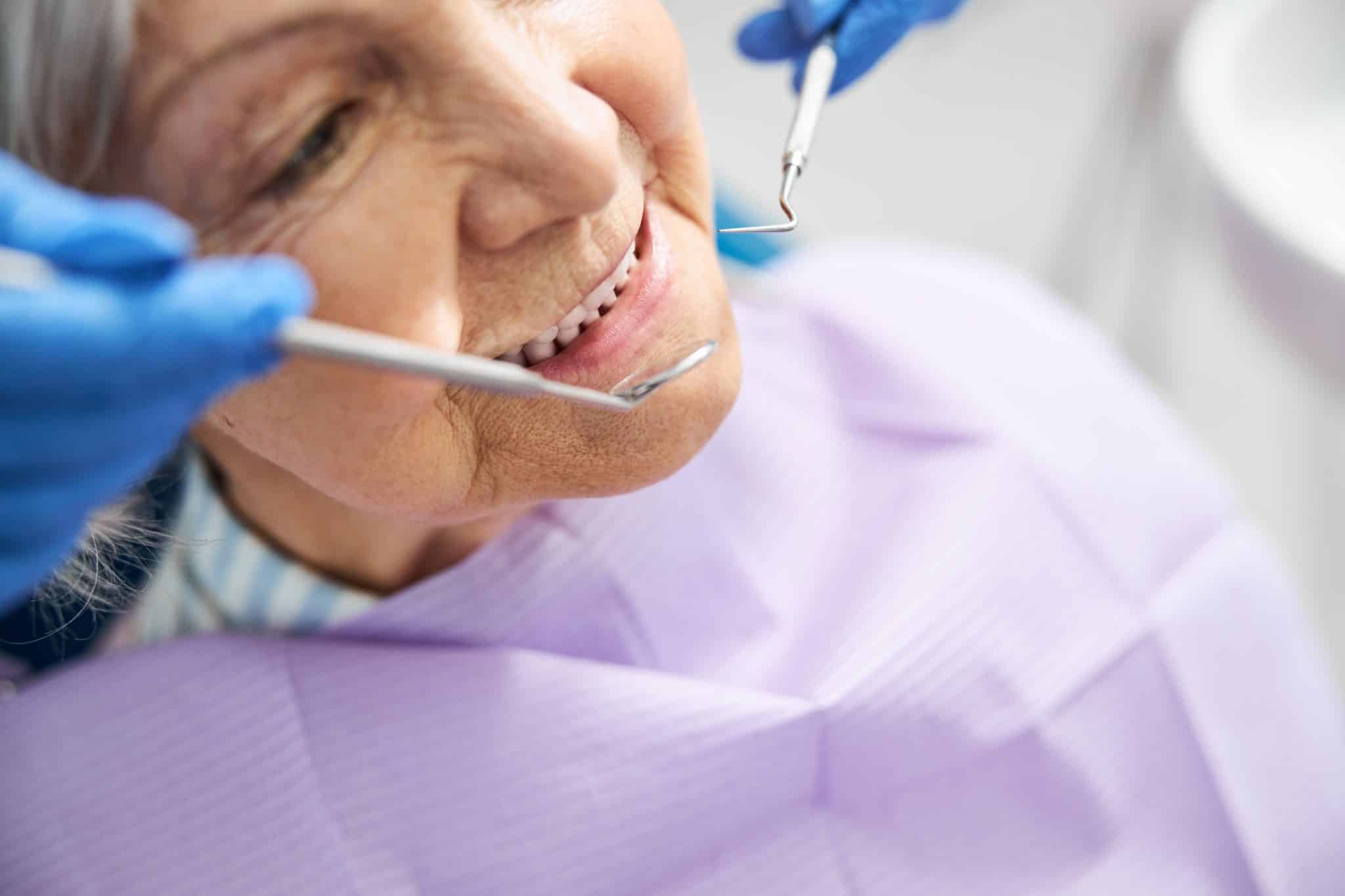 Das Foto zeigt eine ältere Frau in der Zahnarztpraxis bei der Zahnprophylaxe.
