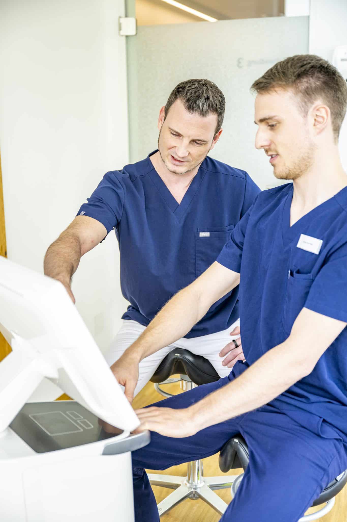 Zwei Zahnärzte analysieren ein digitales Zahnmodell am Monitor des CEREC-Systems.