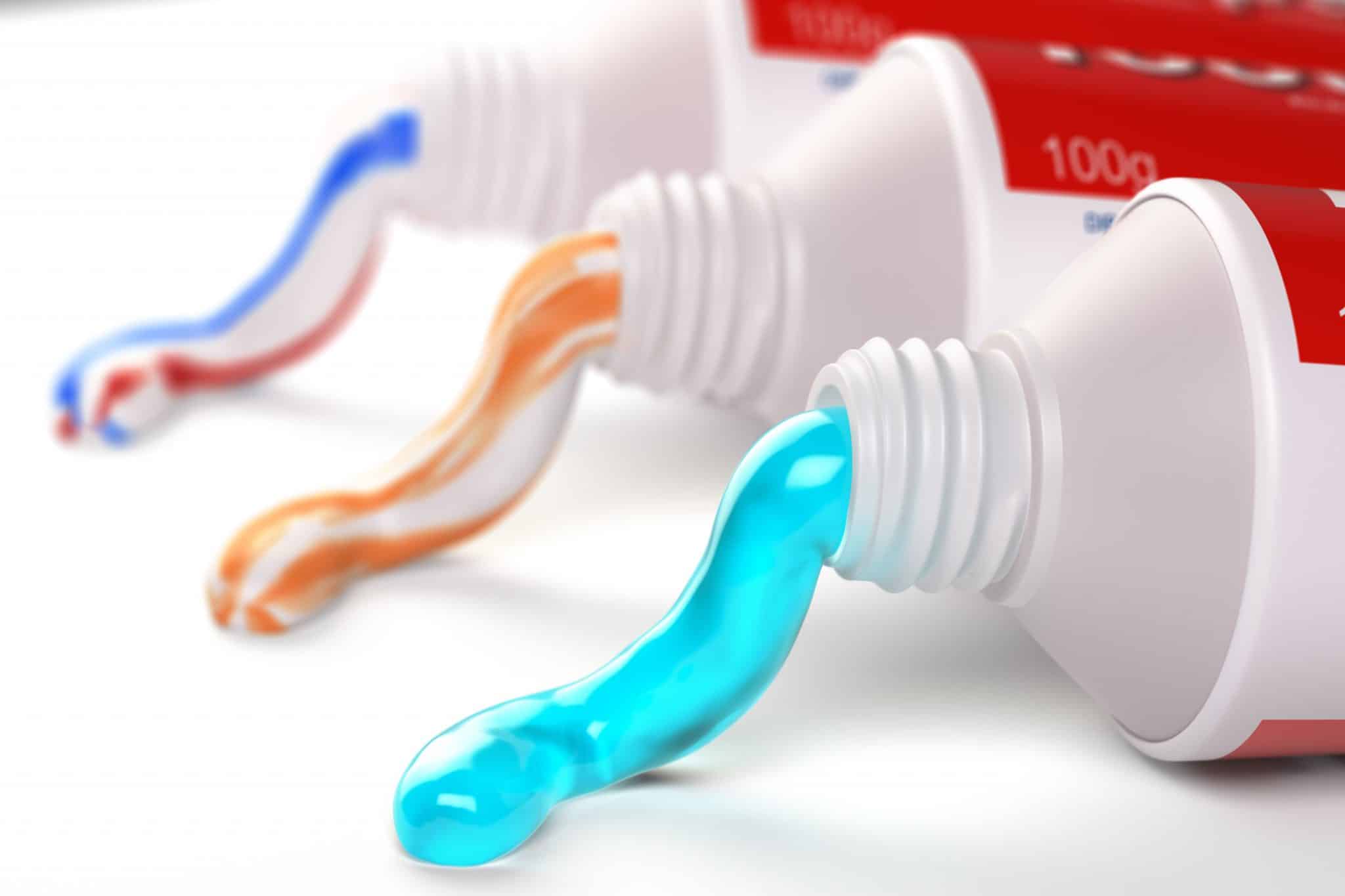 Das Foto zeigt auf weißem Hintergrund Zahnpastatuben mit 3 verschieden farbigen Zahnpasta Produkten.