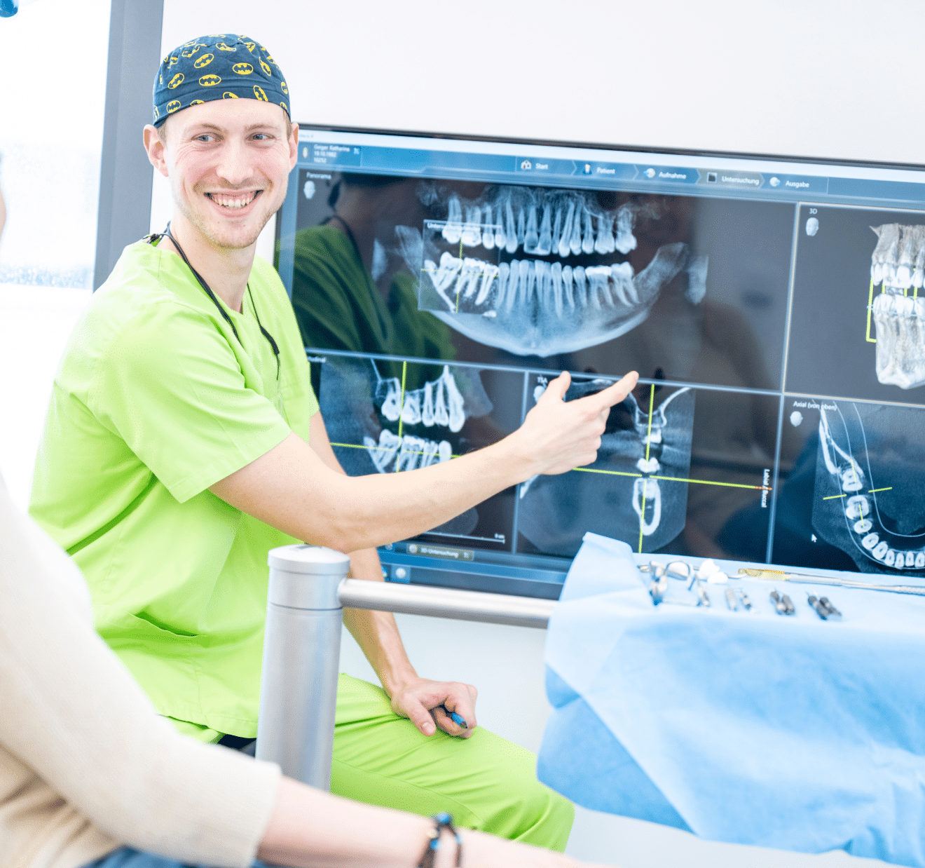 Ein Zahnarzt erklärt im Behandlungszimmer einer Patientin am Bildschirm die Röntgenbilder ihrer Zähne.